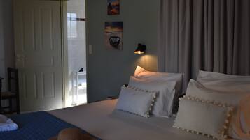 A bedroom with a bed, pillows, a hat, and a wall-mounted lamp.