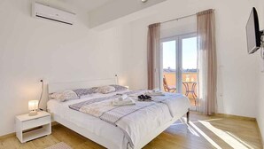 A bedroom with a bed, bedside table, and an air conditioning unit. - Villa with swimming pool and children's playground (Pula)