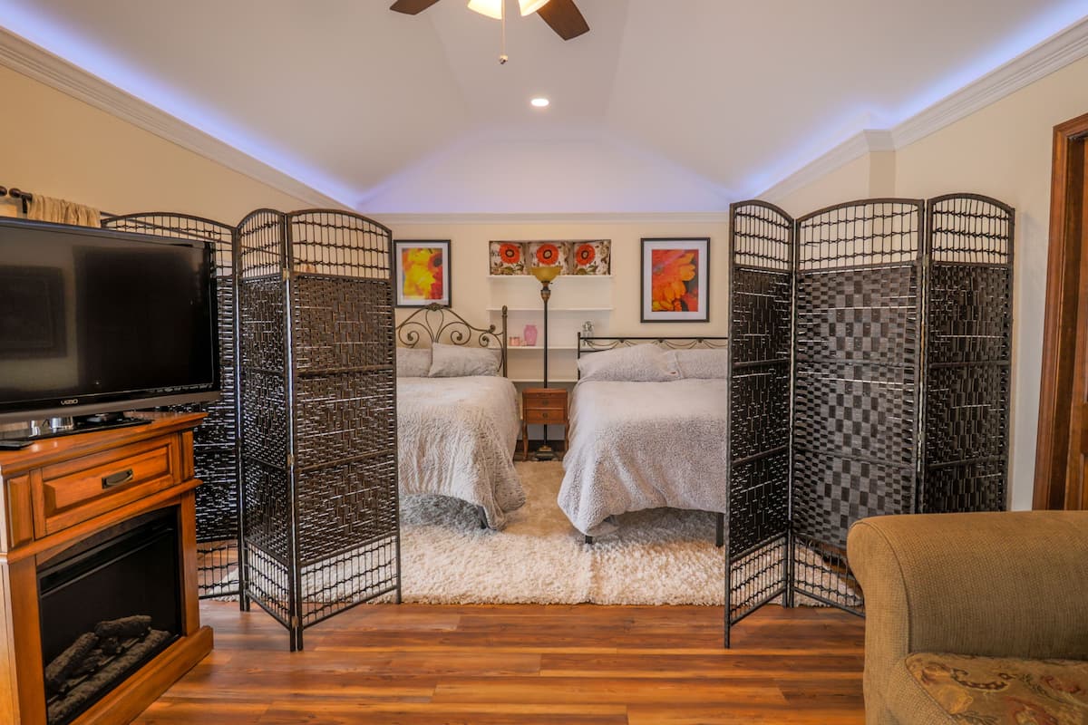 A bedroom with two beds, a TV, and a decorative screen divider.