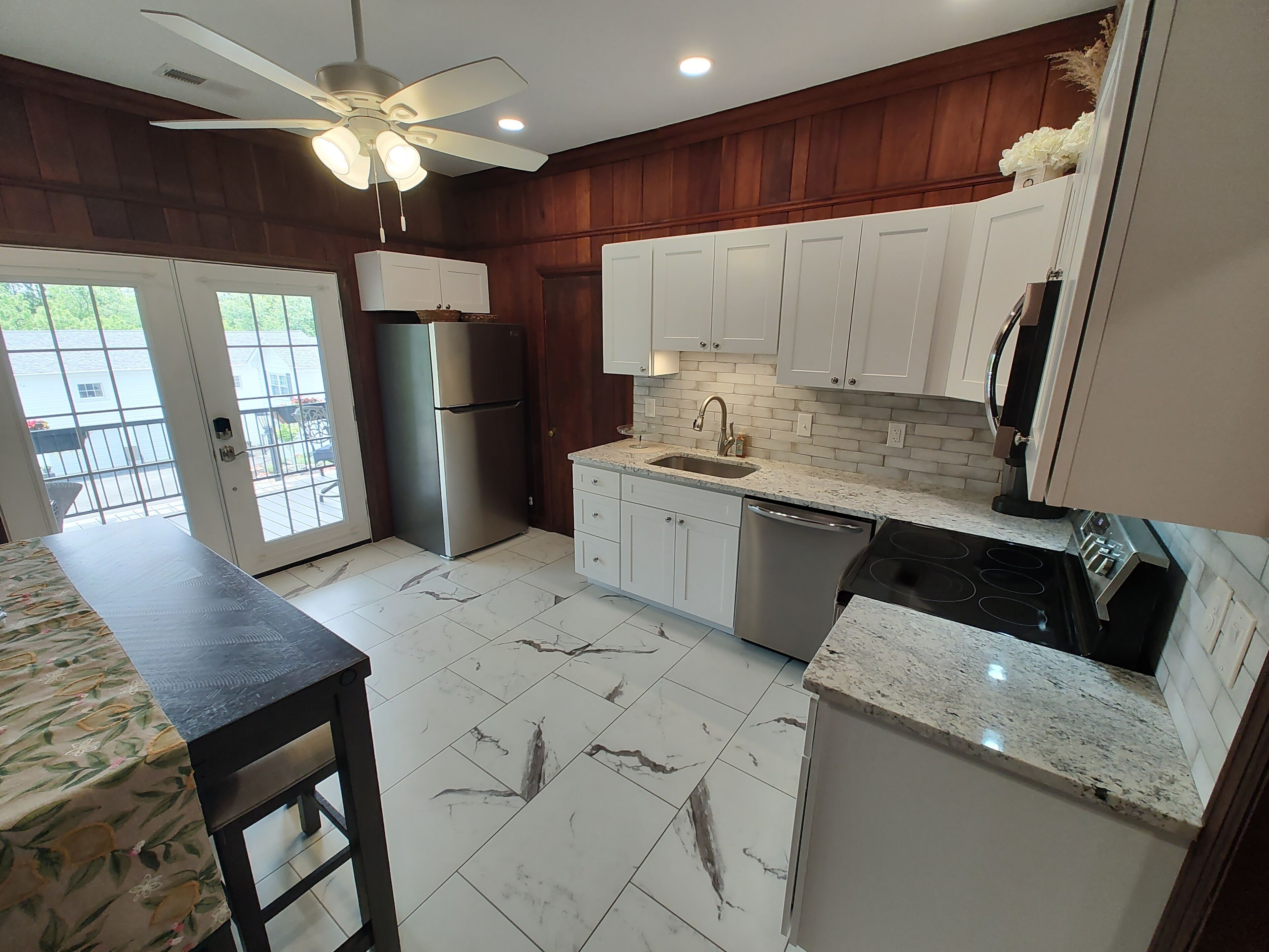 A kitchen with white cabinets, a stainless steel refrigerator, a dishwasher, and a granite countertop.