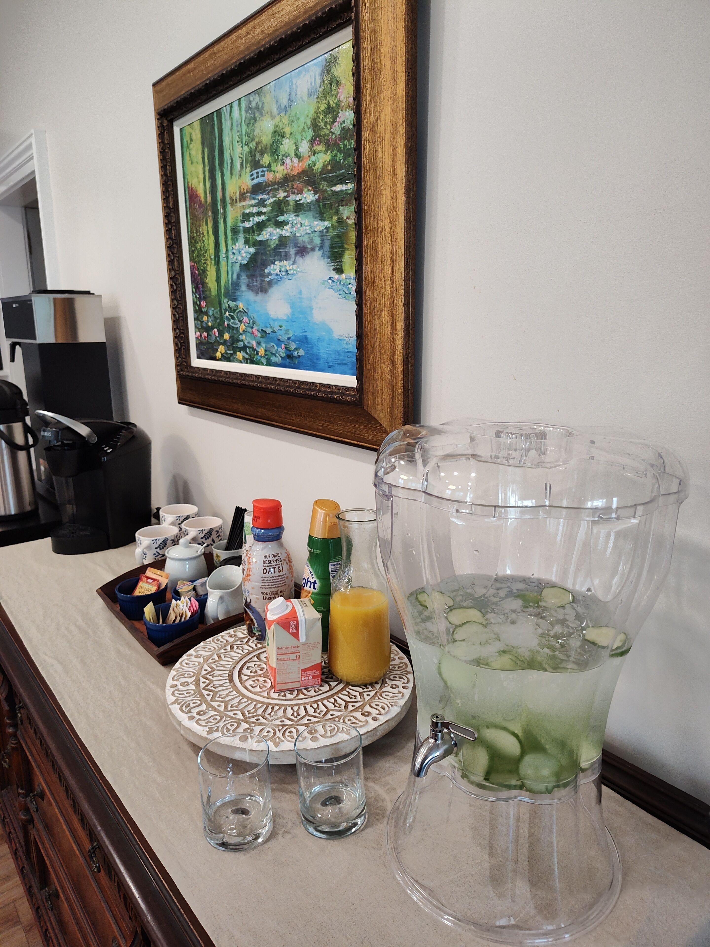Een keukentafel met een blender, een schaal met ontbijtartikelen en een schilderij aan de muur.