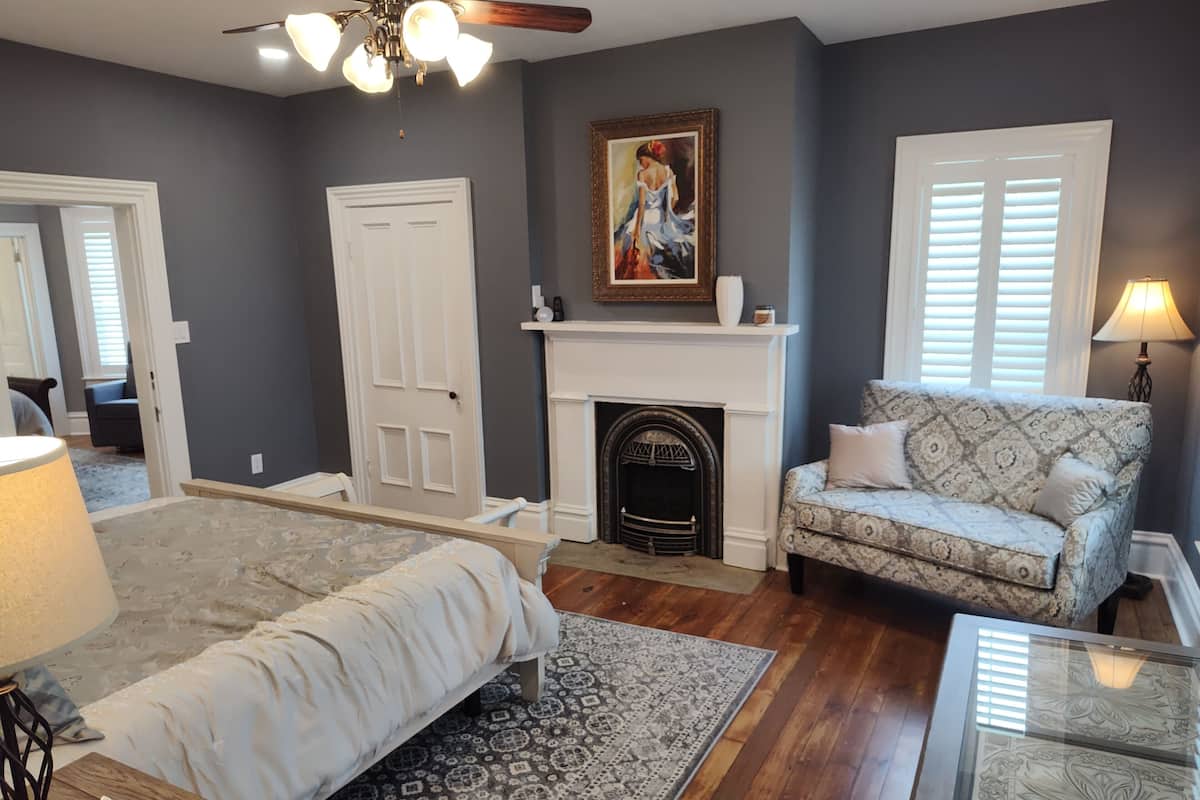 A living room with a fireplace, a sofa, a bed, and a glass coffee table.