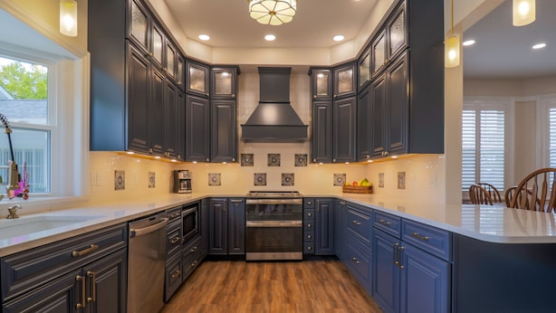 A modern kitchen with dark cabinetry, a central island, and a built-in oven. - Hickory House Bed & Breakfast (Hickory)