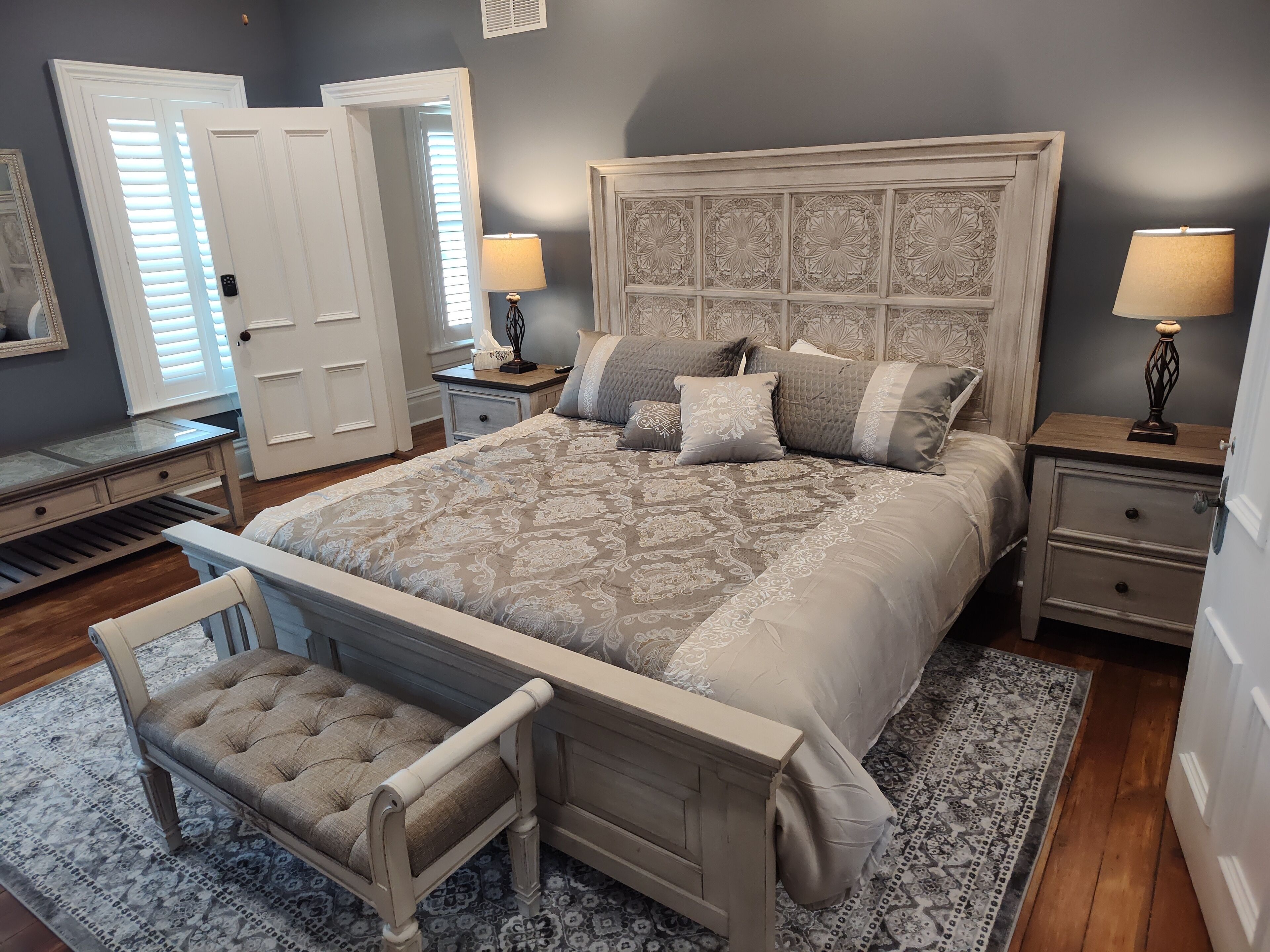 A bedroom with a large bed, a nightstand, a chair, and a dresser.