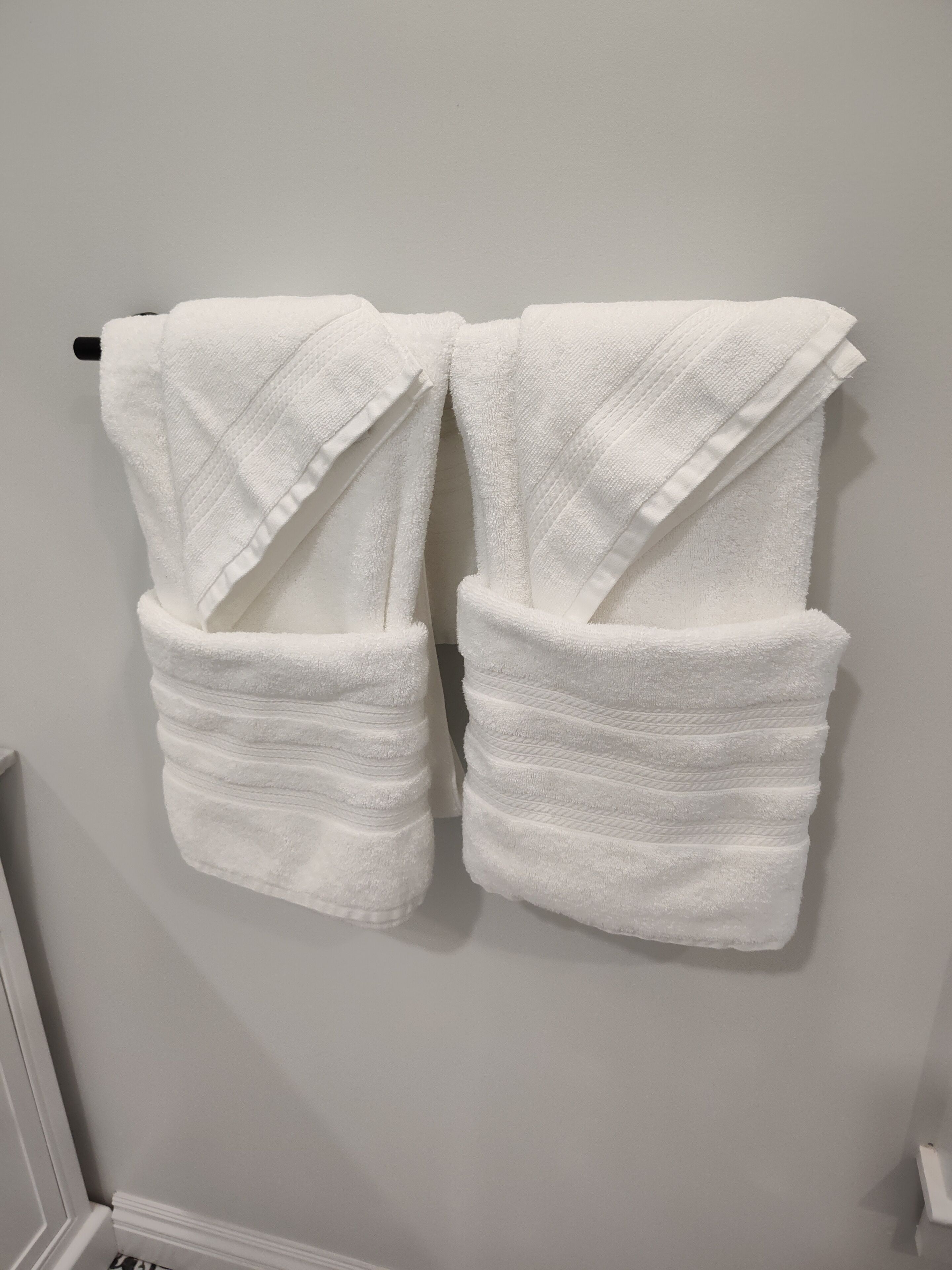 Two white towels hanging on a wall.