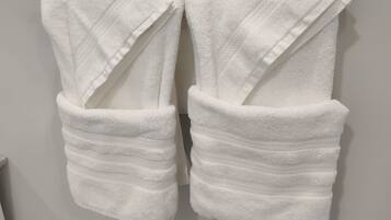 Two white towels hanging on a wall.