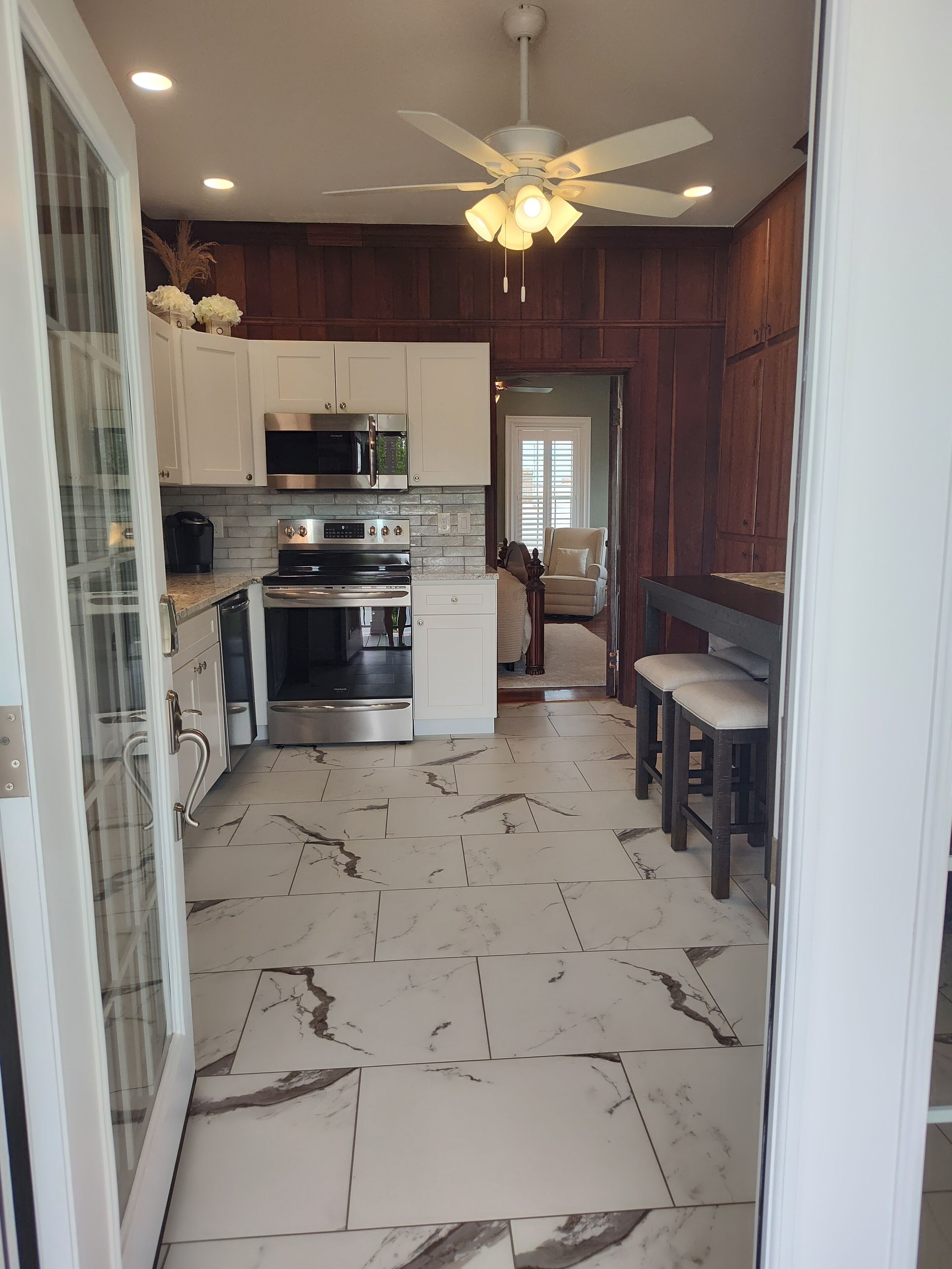 A modern kitchen with white cabinets, a built-in microwave, stainless steel appliances, and a marble floor.
