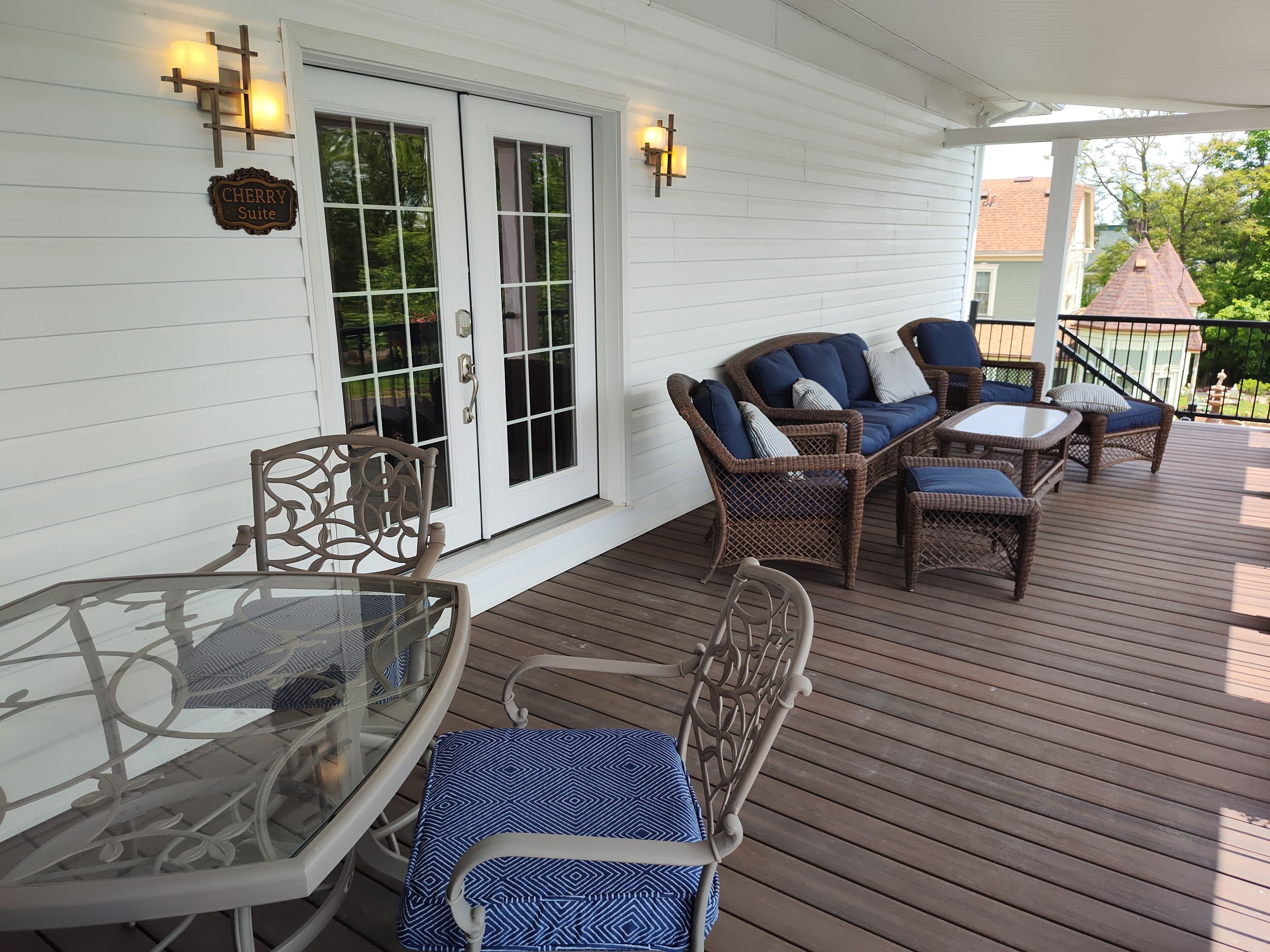 A covered porch with wicker furniture, a glass table, and a sign reading "CHERRY Suite".