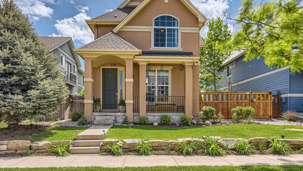 A two-story house with a front porch, a large window, and a well-maintained lawn.
