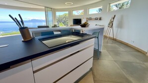 Een moderne keuken met uitzicht op zee, een eethoek en een werkplek.