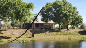 Ein Haus mit Teich, umgeben von Bäumen und einer Rasenfläche.