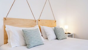 A bed with a wooden headboard, white bedding, and two decorative pillows.