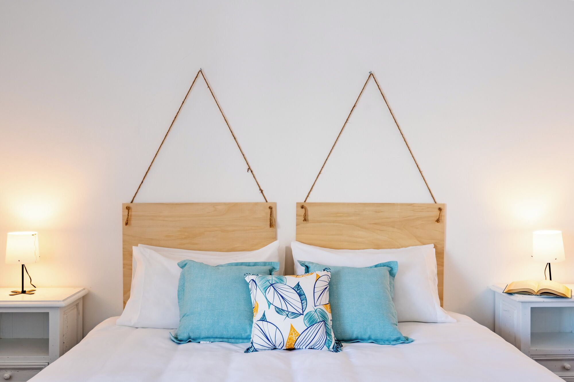 A double bed with a wooden headboard, two bedside tables with lamps, and decorative pillows.