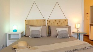 Ein Doppelbett mit Holz Kopfteil, zwei Nachttische und je eine Lampe an jeder Seite.
