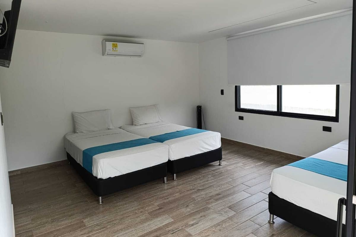 Una habitación con dos camas, una ventana y un equipo de aire acondicionado.