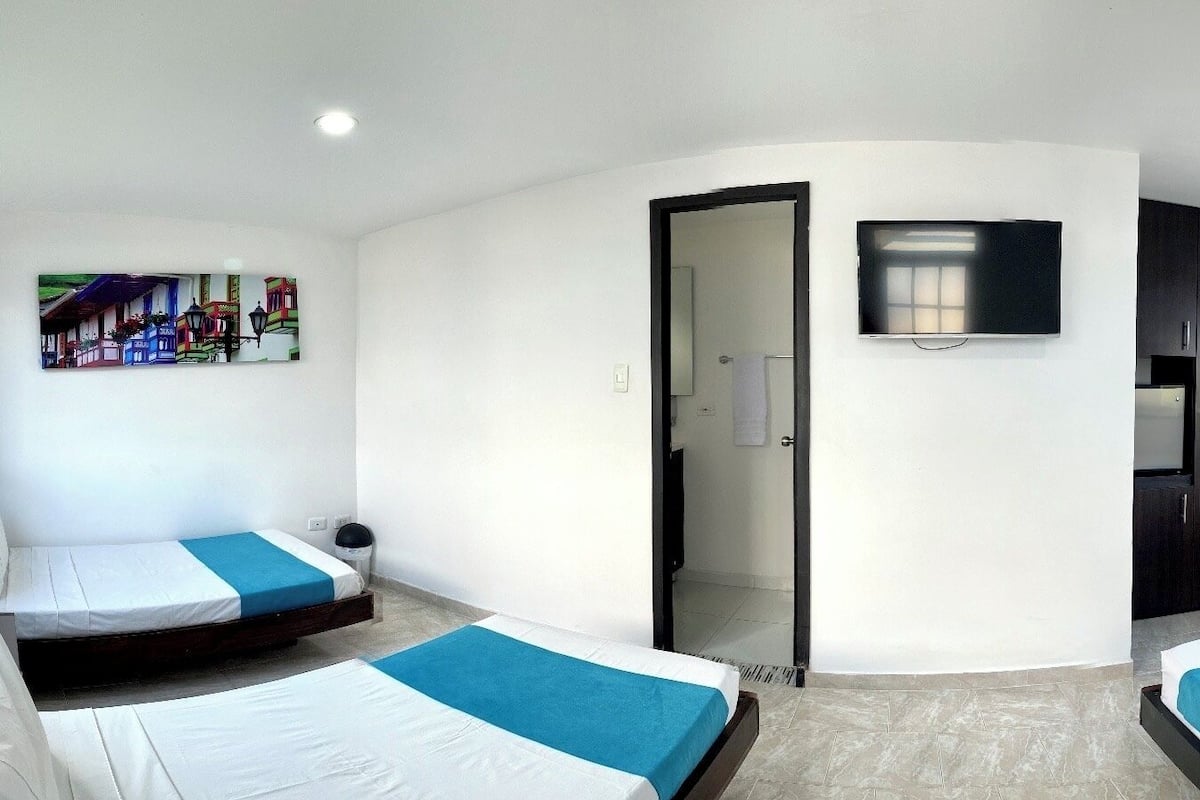 Habitación de hotel con dos camas, un televisor, un cuadro y una ventana con vistas.