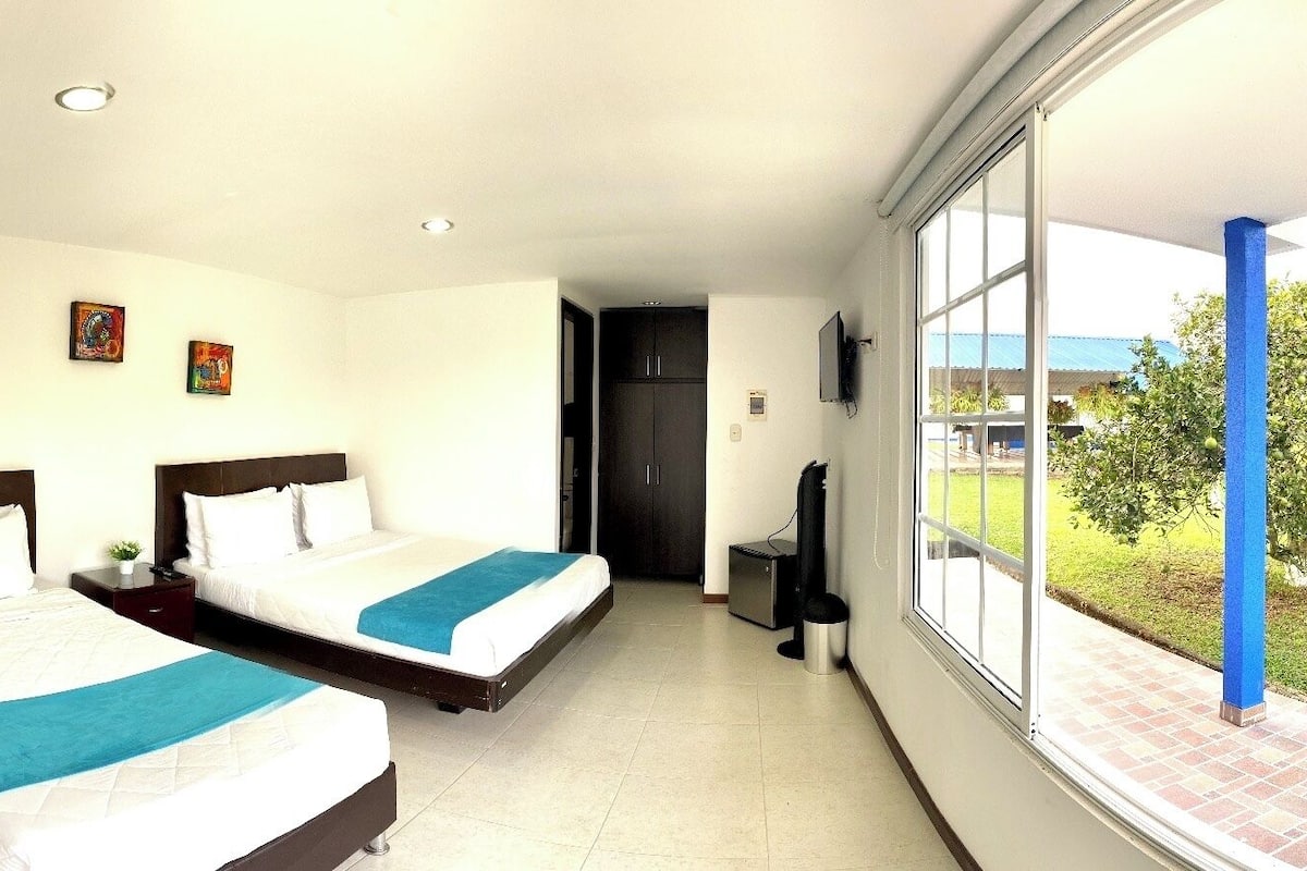Habitación de hotel con dos camas, un ventanal grande y vistas al exterior.
