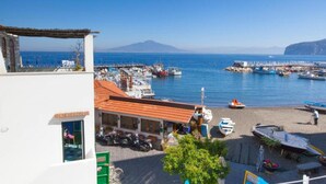 Un pueblo costero con un puerto deportivo, barcos y un edificio de techo rojo.
