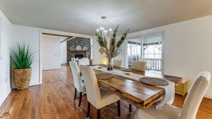 A dining area with a wooden table, white chairs, and a large potted plant. - Bryson City Mtn Retreat w/ Hot Tub (Bryson City)