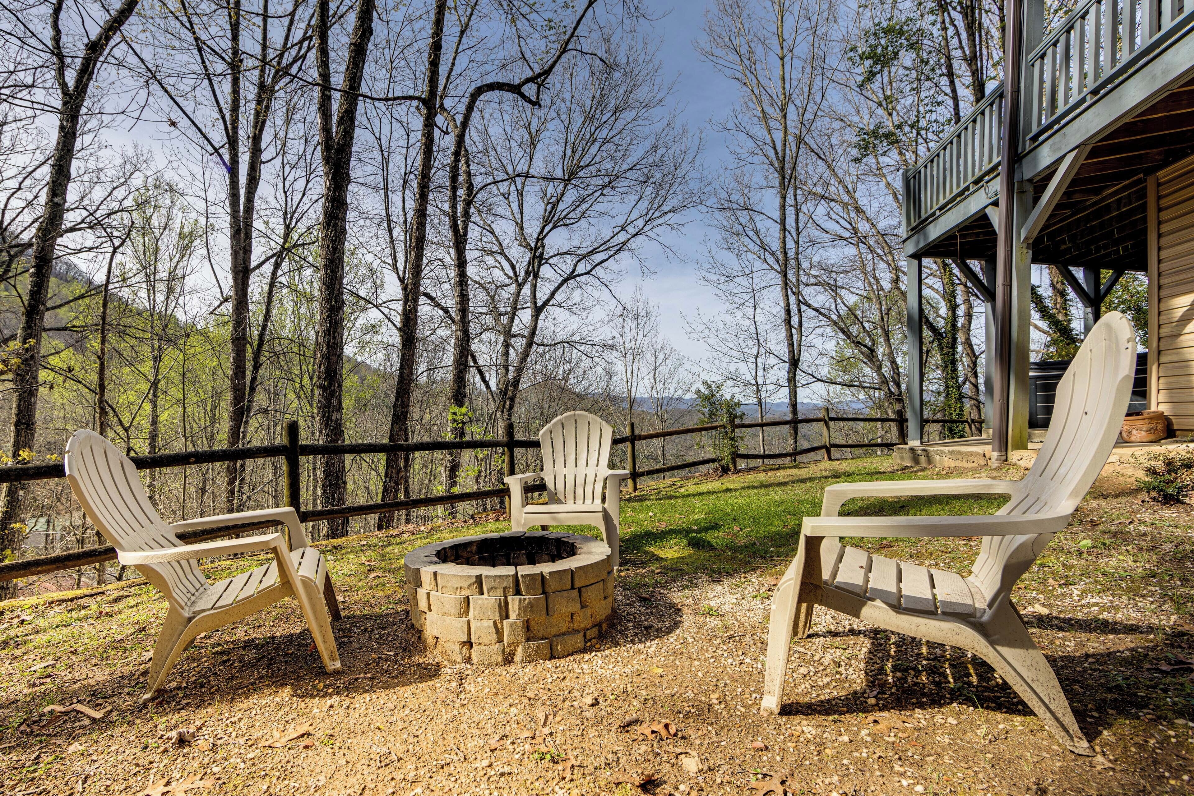 A deck with Adirondack chairs and a fire pit, surrounded by trees and a wooden fence.