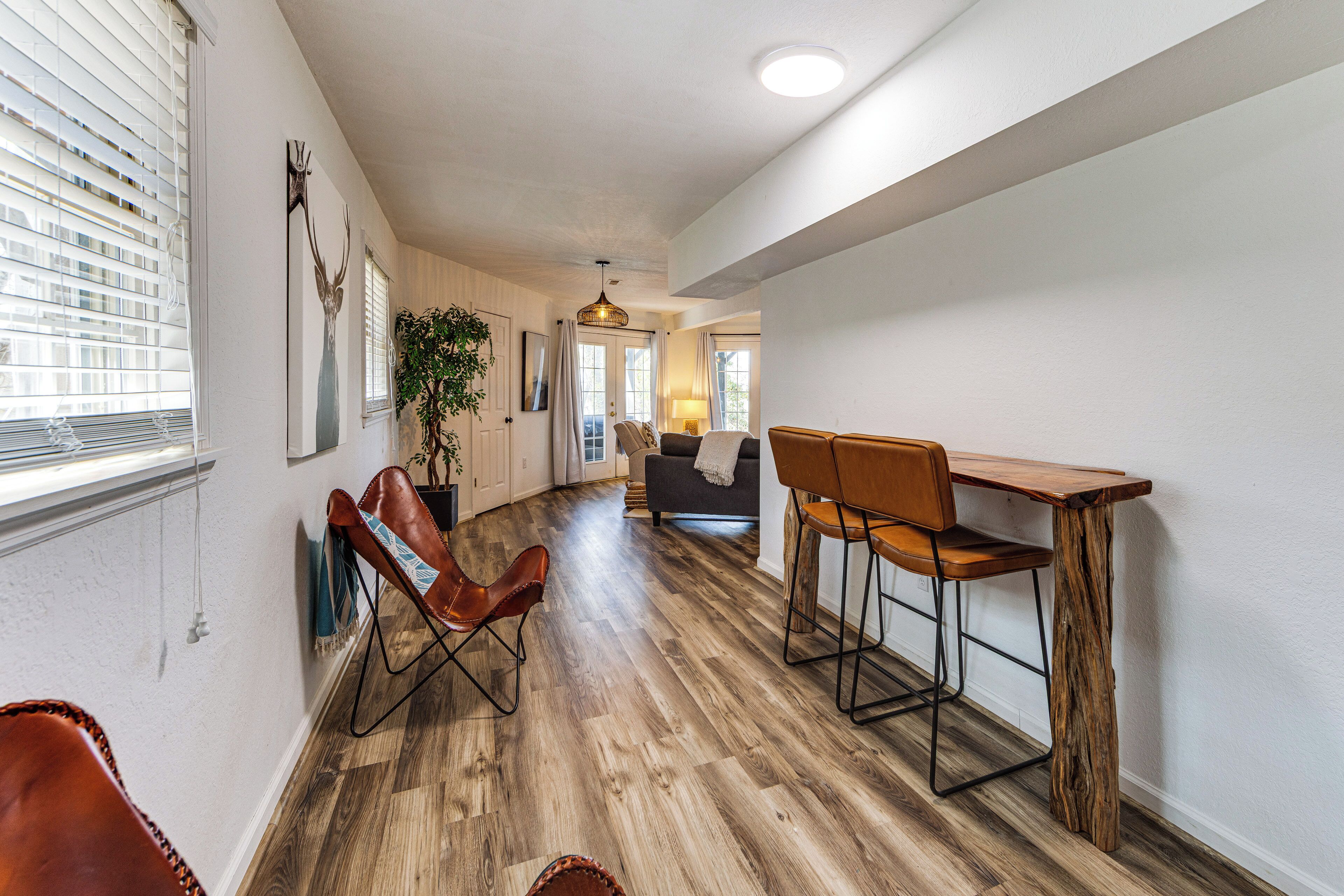 A spacious hallway with a dining area, a sofa, and a plant.