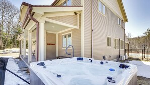 Ein Whirlpool vor einem zweistöckigen Haus mit einer Veranda.