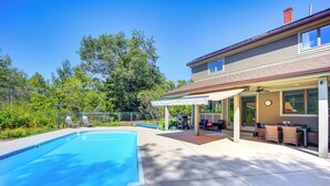 Ein Wohnhaus mit Swimmingpool, Terrassenmöbeln und einer überdachten Sitzgelegenheit im Freien.