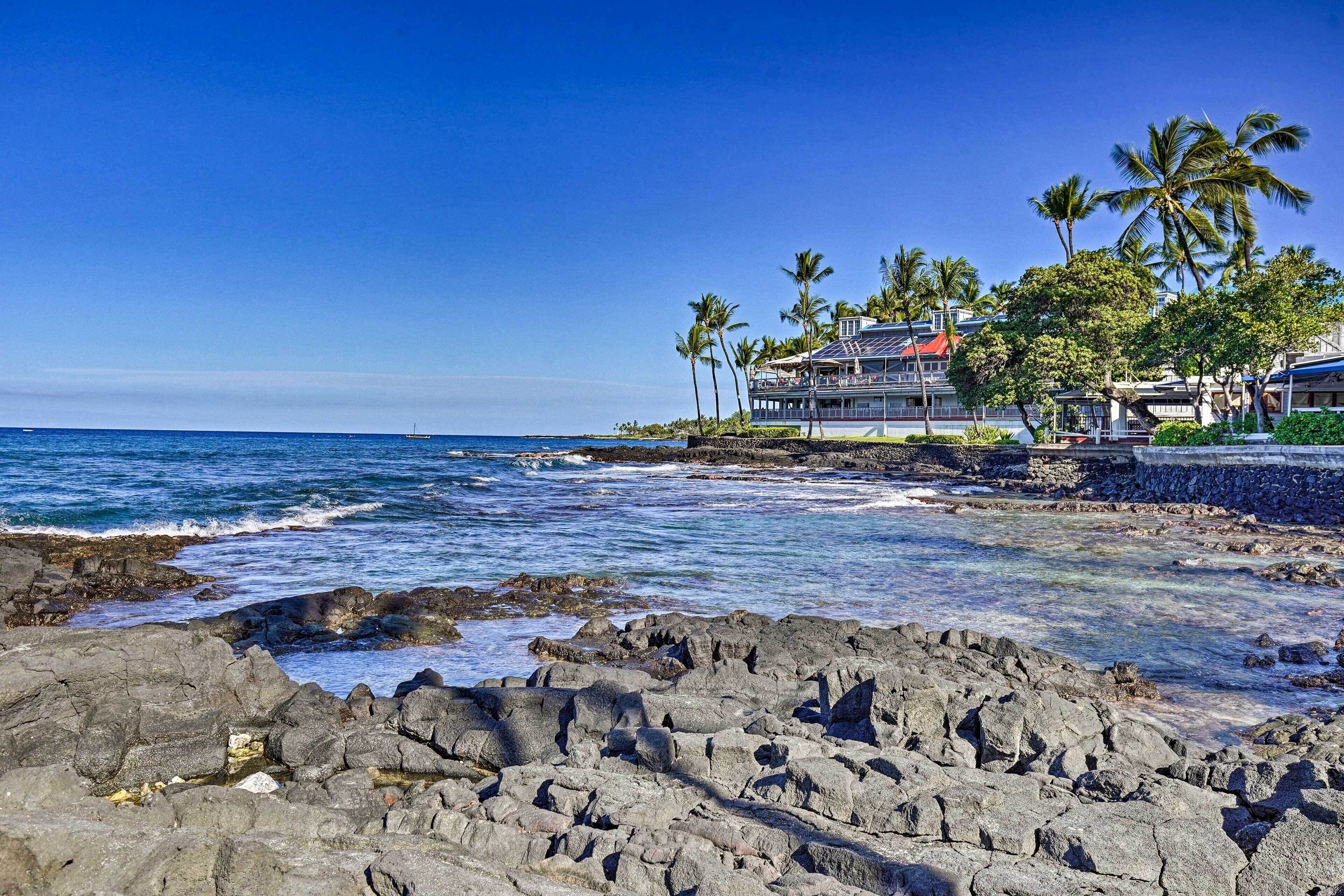 Un hôtel situé sur la côte, avec un rivage rocheux, des palmiers et une vue sur l’océan.