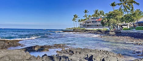 Un hôtel situé sur la côte, avec un rivage rocheux, des palmiers et une vue sur l’océan.