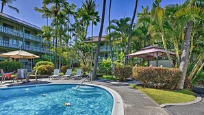 A swimming pool with a 'NO DIVING' sign, surrounded by lounge chairs and palm trees.