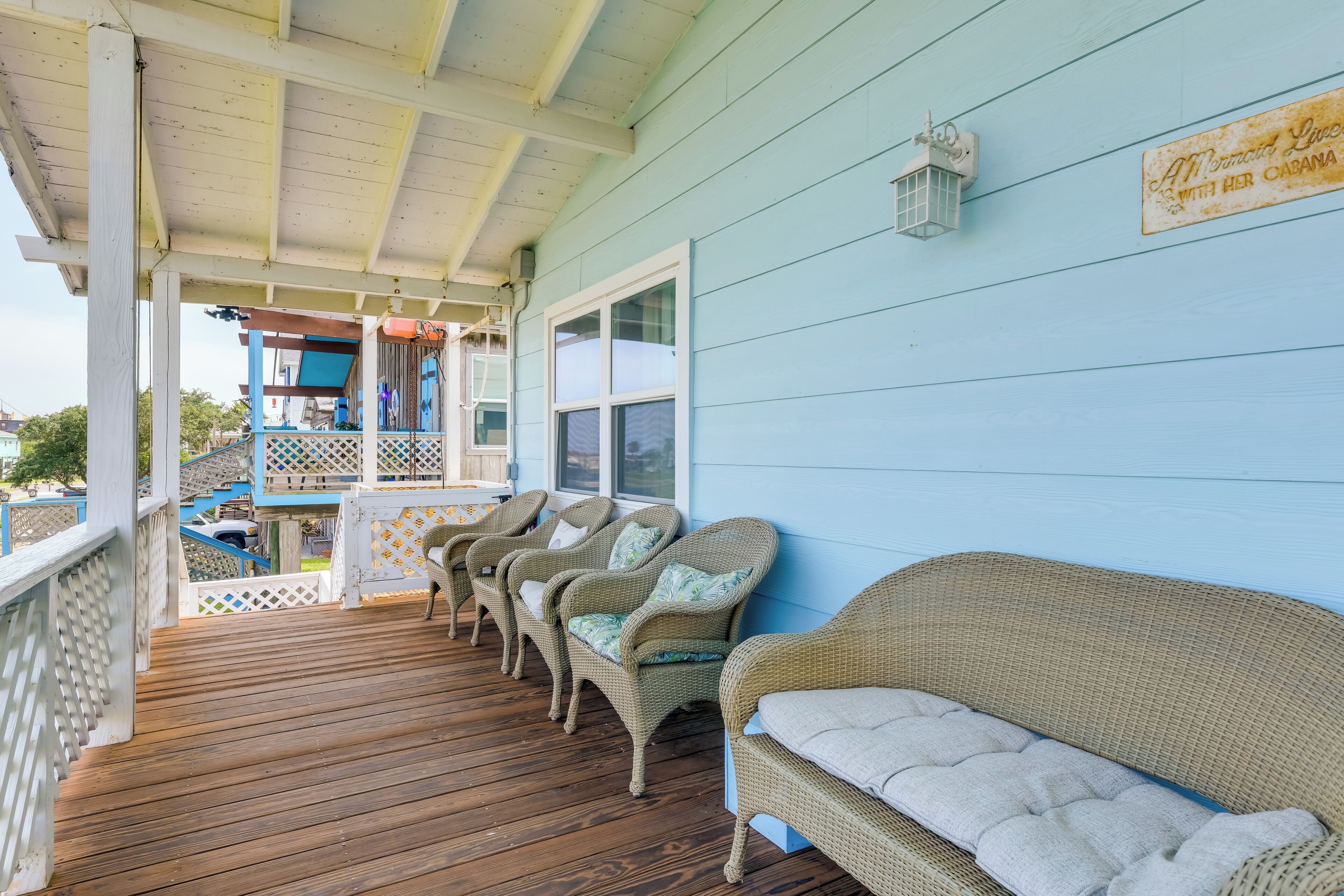 A covered porch with wicker furniture and a wooden deck.