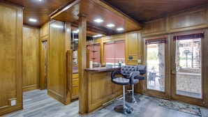 A wooden interior with a bar area, a staircase, and a view through a glass door. - Outdoor Pool & Lake: Massive Texas Ranch Villa! (Commerce)