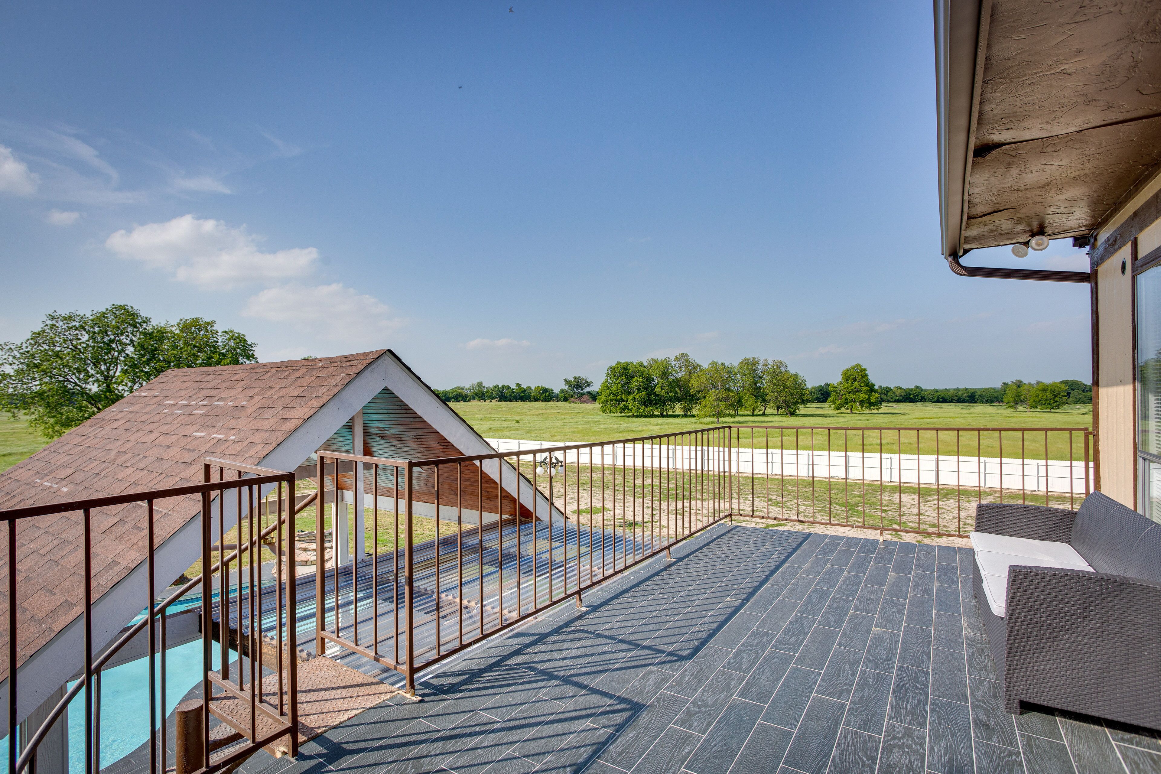 A balcony with a view of a swimming pool and a grassy field.