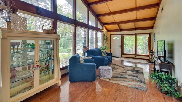 Un salón amplio con techo alto, ventanas grandes y piso de madera.