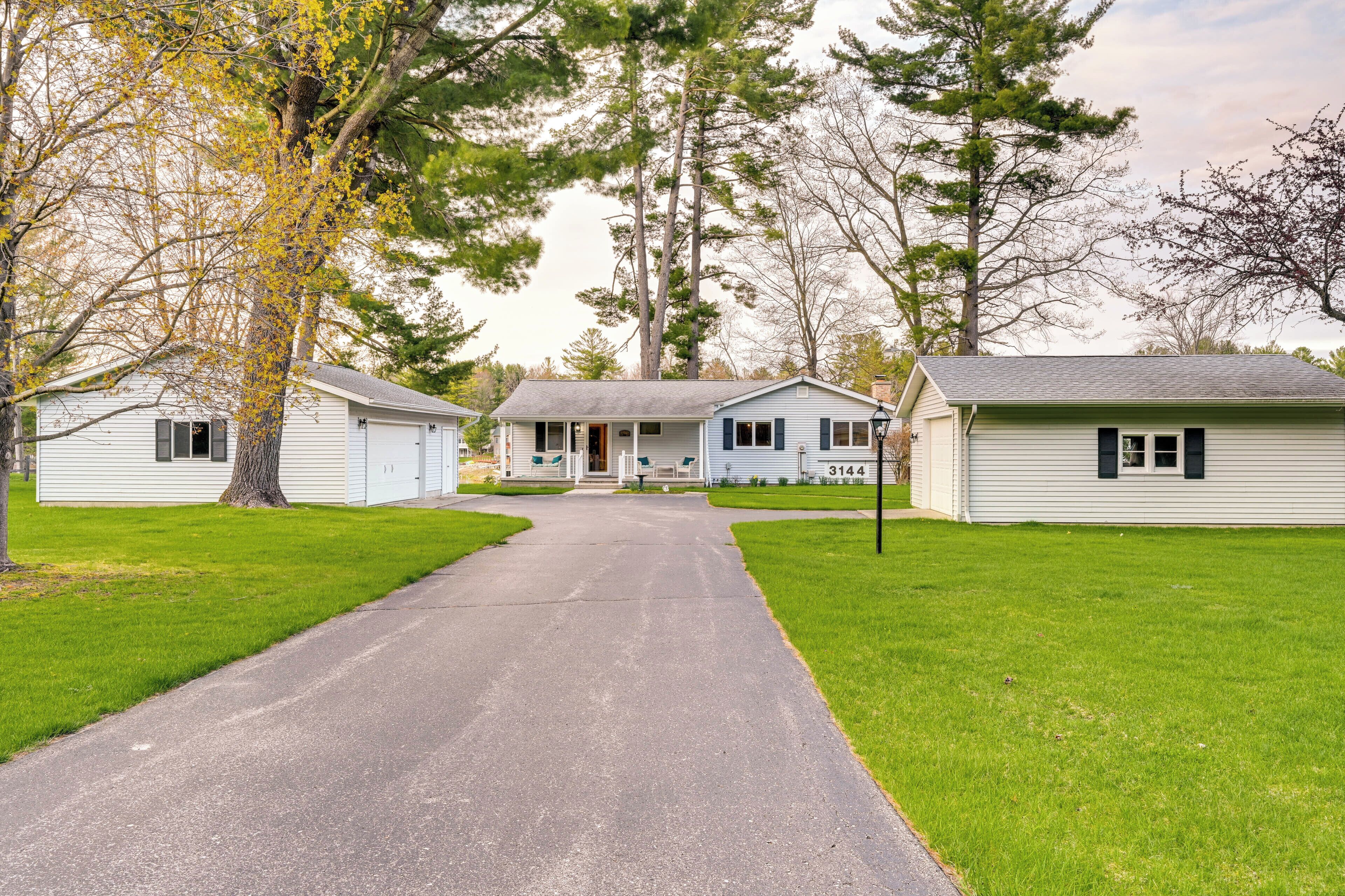 A residential street with two single-story houses, a paved driveway, and well-maintained lawns.