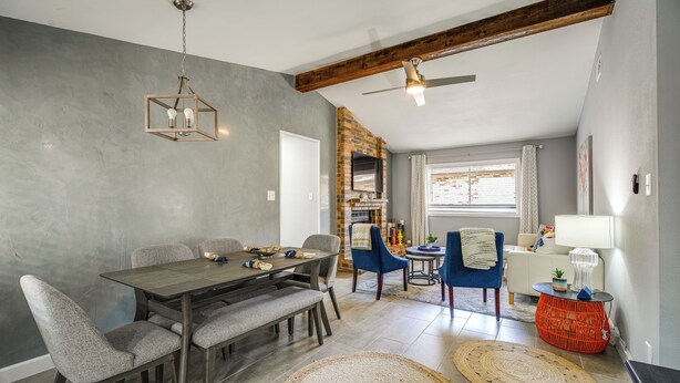 A dining area with a wooden table and chairs, a ceiling fan, and a brick fireplace. - Serene San Antonio Vacation Home w/ Smart TVs (San Antonio)