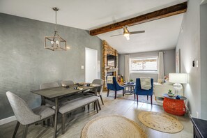 A dining area with a wooden table and chairs, a ceiling fan, and a brick fireplace. - Serene San Antonio Vacation Home w/ Smart TVs (San Antonio)
