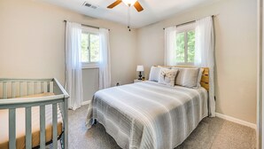 A bedroom with a bed, a crib, a ceiling fan, and two windows with curtains. - 3 Mi to Burnside Marina: Lake Cumberland Getaway (Somerset)