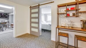 Ein Zimmer mit einer Schiebetür, die zum Schlafbereich führt, einer Küchenzeile mit Holzböden und einem gemusterten Teppich.