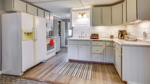 Eine Küche mit weißen Schränken, einem Kühlschrank, einem Backofen, einer Mikrowelle und einem Spülbecken.