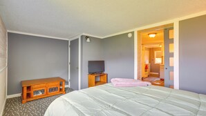 Ein Schlafzimmer mit einem Bett, einem Holzschrank, einem Fernseher und einer Tür zu einem weiteren Raum.