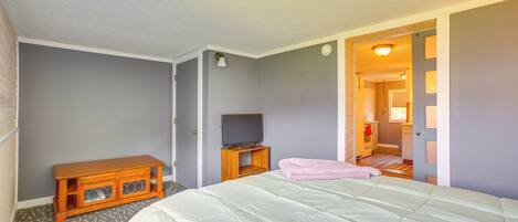 A bedroom with a bed, a wooden cabinet, a television, and a door leading to another room.