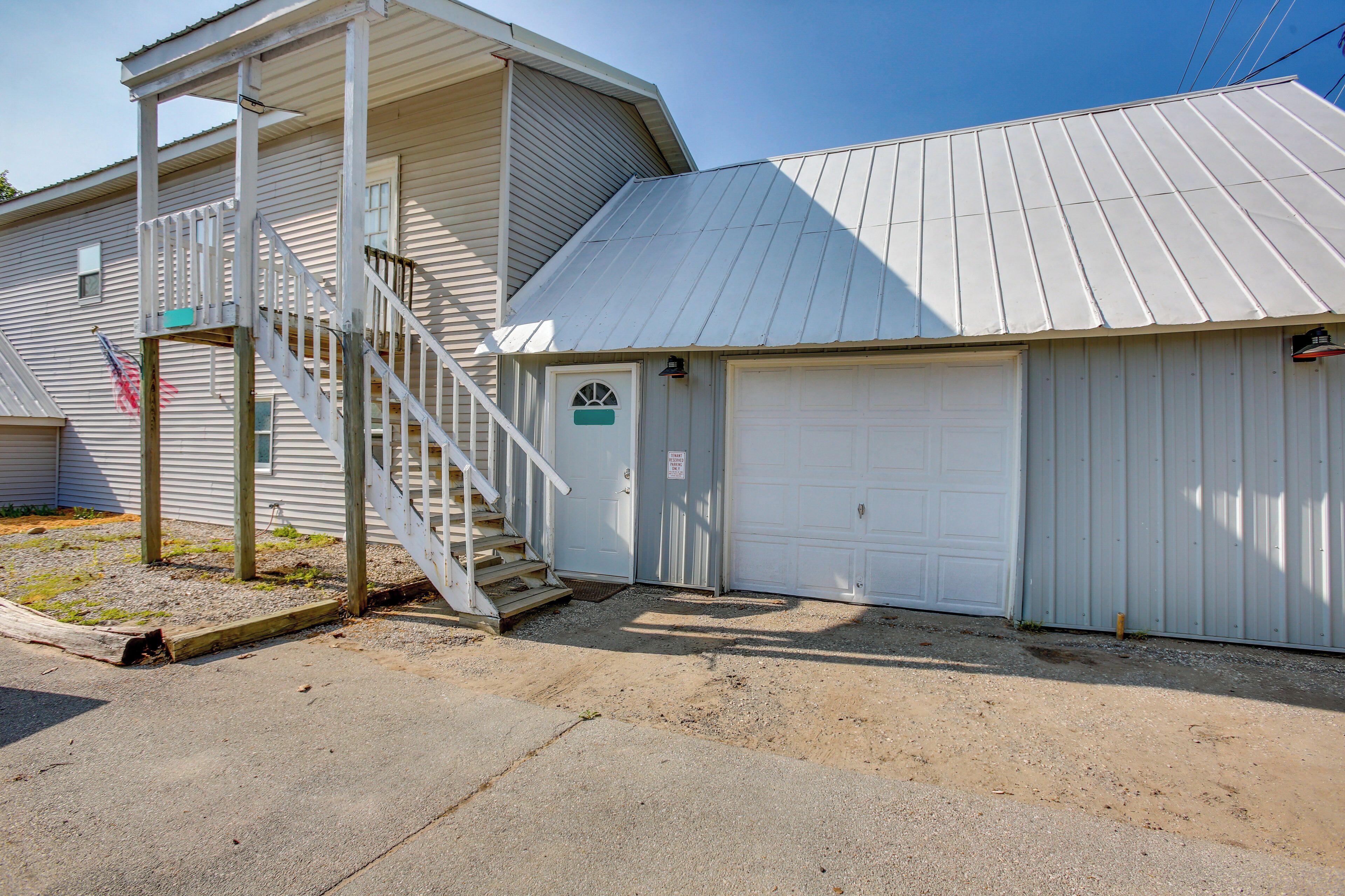 A two-story building with a covered garage and a staircase leading to the upper floor.