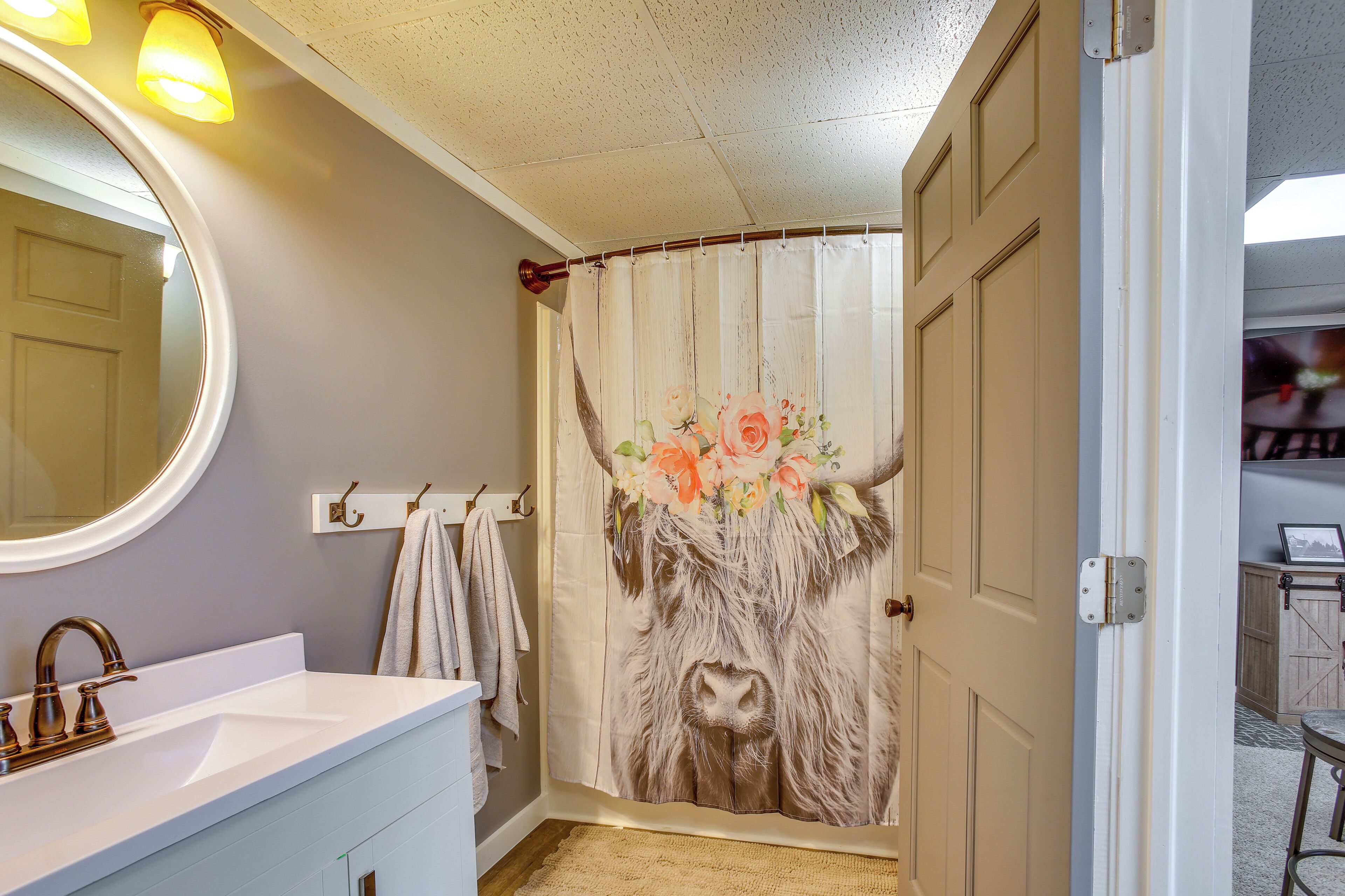 A bathroom with a white sink, a round mirror, and a shower curtain with a floral design.