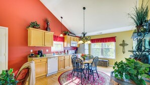 Une cuisine avec des meubles de rangement en bois, une table à manger avec des chaises et un tapis rouge.