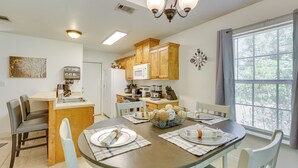 A modern kitchen with wooden cabinets, a microwave, and a dining area with a round table set for four. - Charming Abbeville Home w/ Private Boat Dock! (Abbeville)
