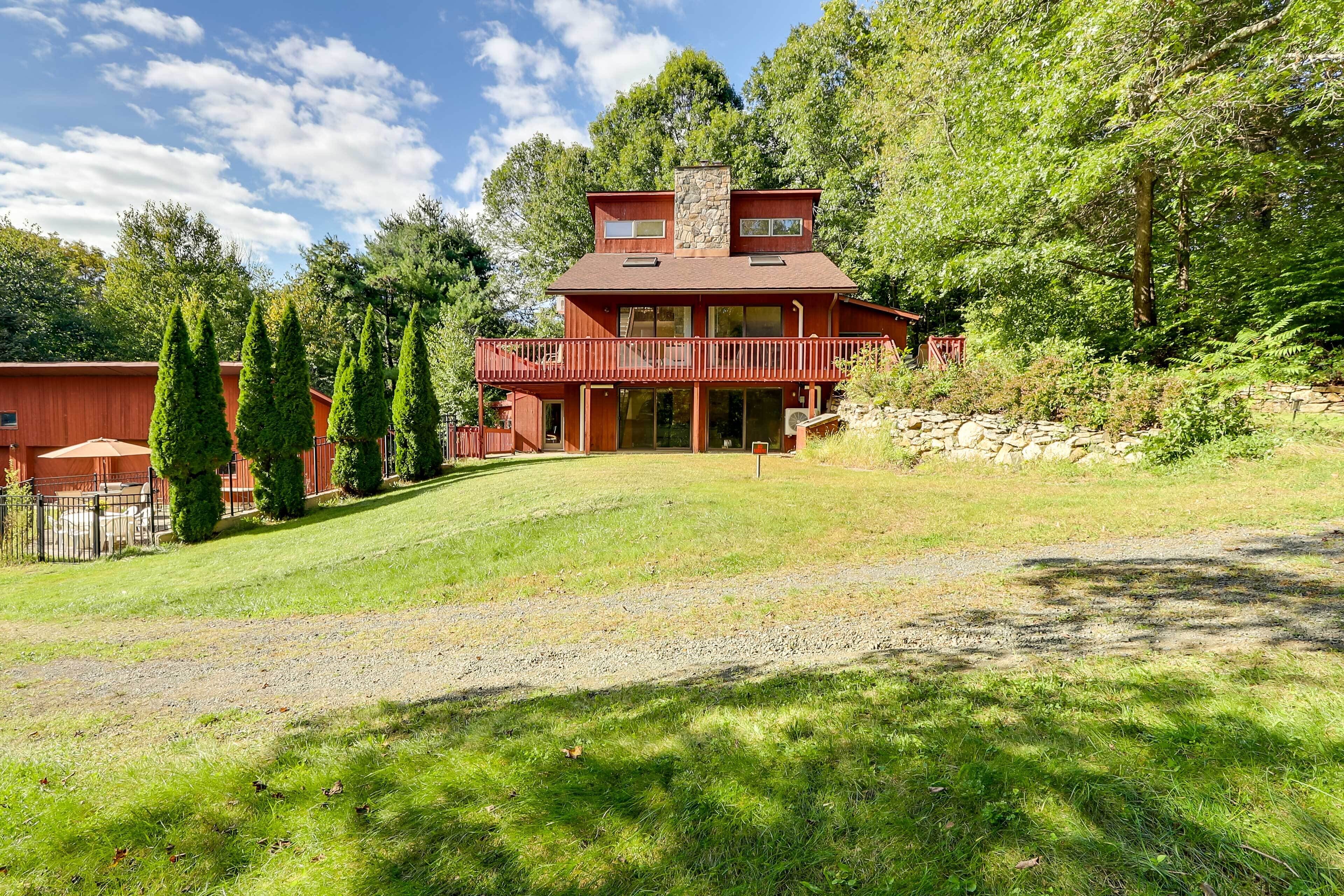 A two-story house with a red exterior, a stone chimney, and a balcony.