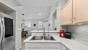 A modern kitchen with stainless steel appliances, a double sink, and light wood cabinets. - Cozy Arizona Retreat w/ Patio, Grill & Pool Access (Mesa)