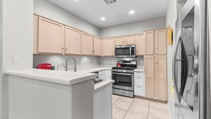 A modern kitchen with light wooden cabinets, stainless steel appliances, and a white countertop. - Cozy Arizona Retreat w/ Patio, Grill & Pool Access (Mesa)