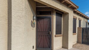A house with a textured beige exterior, a dark brown door with a decorative design, and a small window above the door. - Cozy Arizona Retreat w/ Patio, Grill & Pool Access (Mesa)